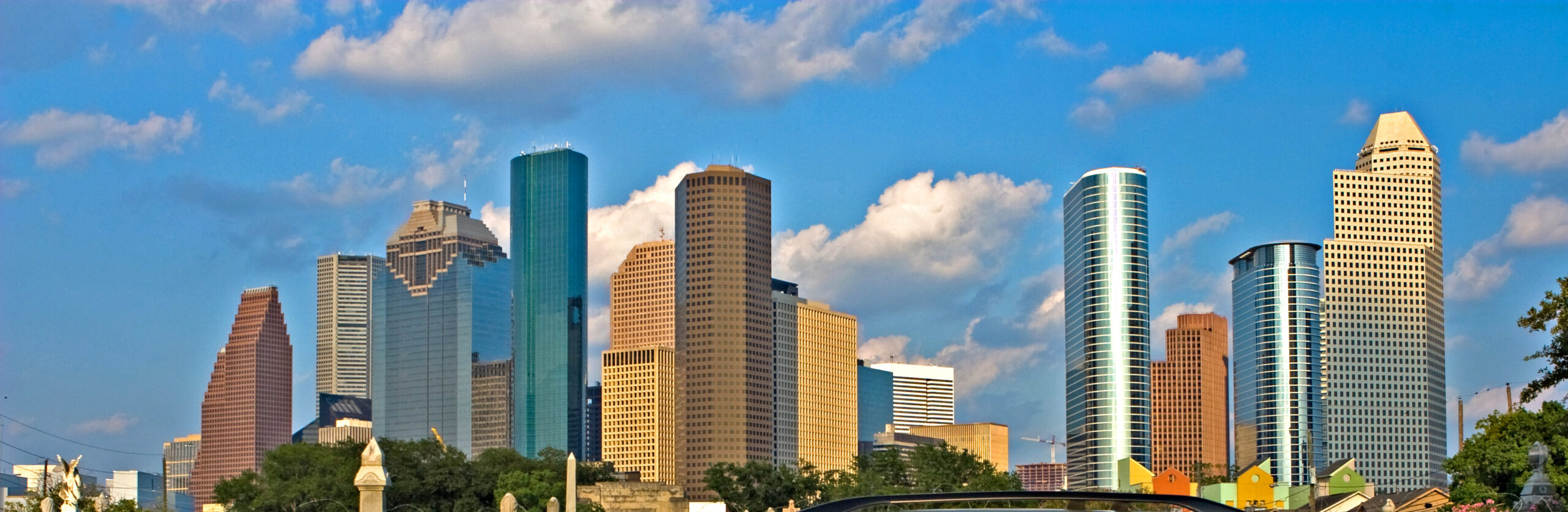 Houston city skyline in broad daylight with blue skies and some clouds